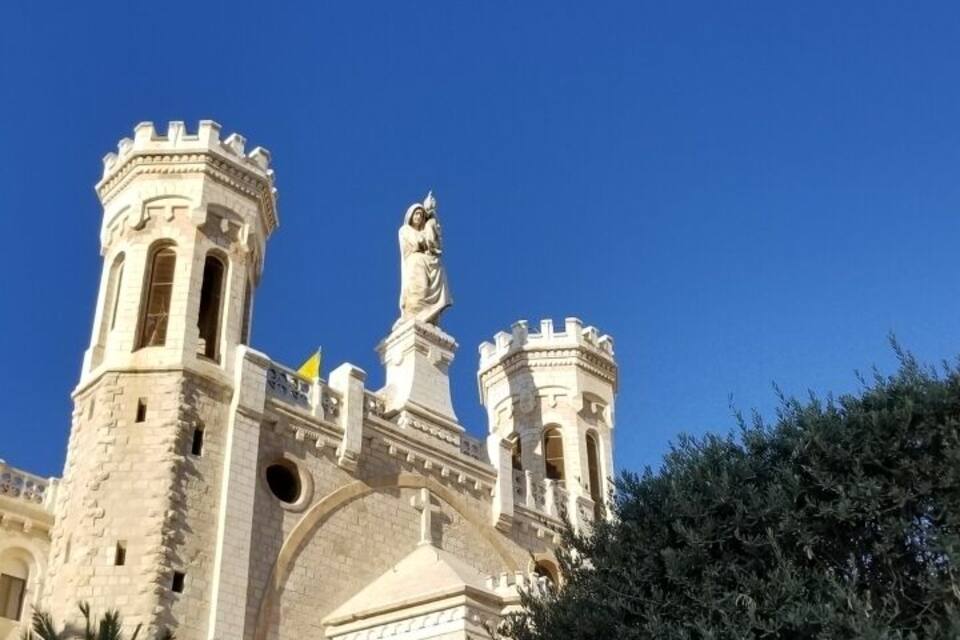 Um edifício histórico com torres e uma estátua.