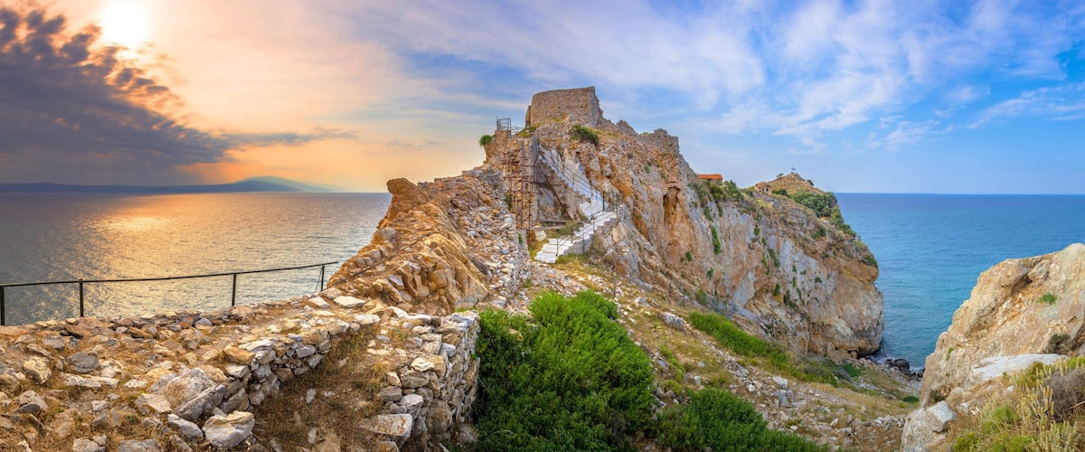 A coastal cliff with ruins and a metal staircase.