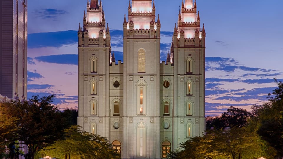 A grand cathedral with three spires, a large central tower, and a reflection in the water in front.