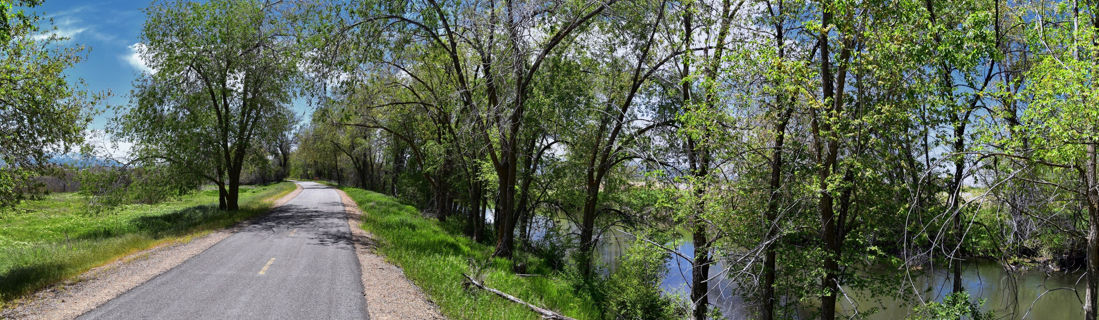 Jordan River Parkway Trail, Redwood Trailhead bordering the Legacy Parkway Trail, panorama views with surrounding trees and silt filled muddy water along the Rocky Mountains, Salt Lake City, Utah. 