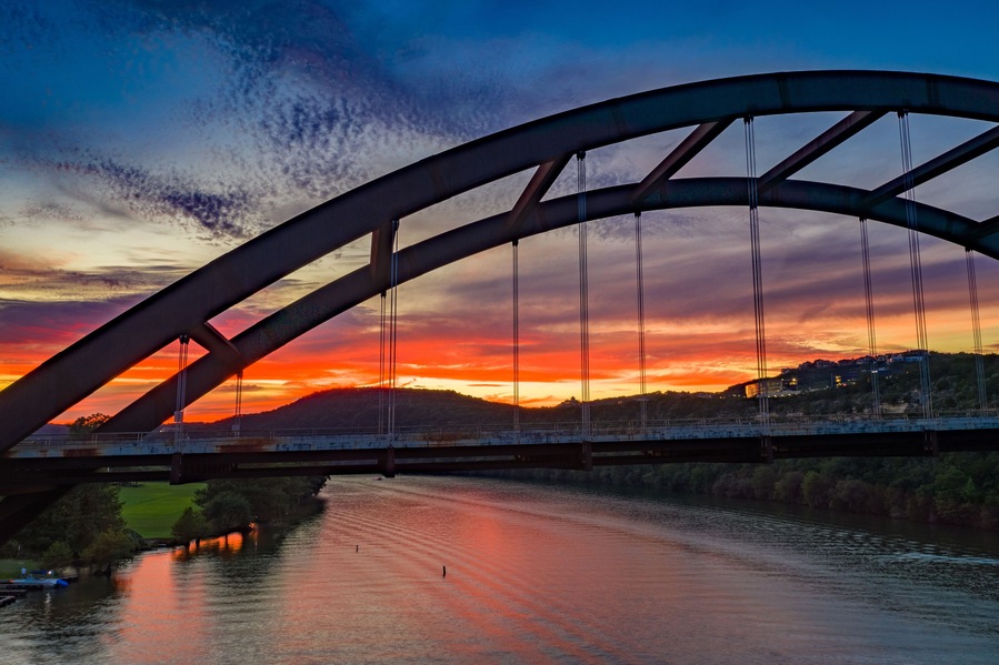 Un puente con un arco curvo sobre un río al atardecer.