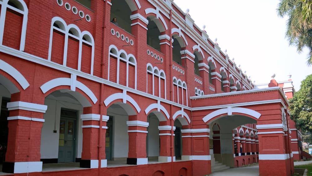 A red brick building with white arches and columns, featuring a large arched entrance and a clock tower.