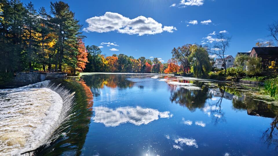 Weir on the Charles River and fall sunshine reflecting in the water at South Natick Dam Park