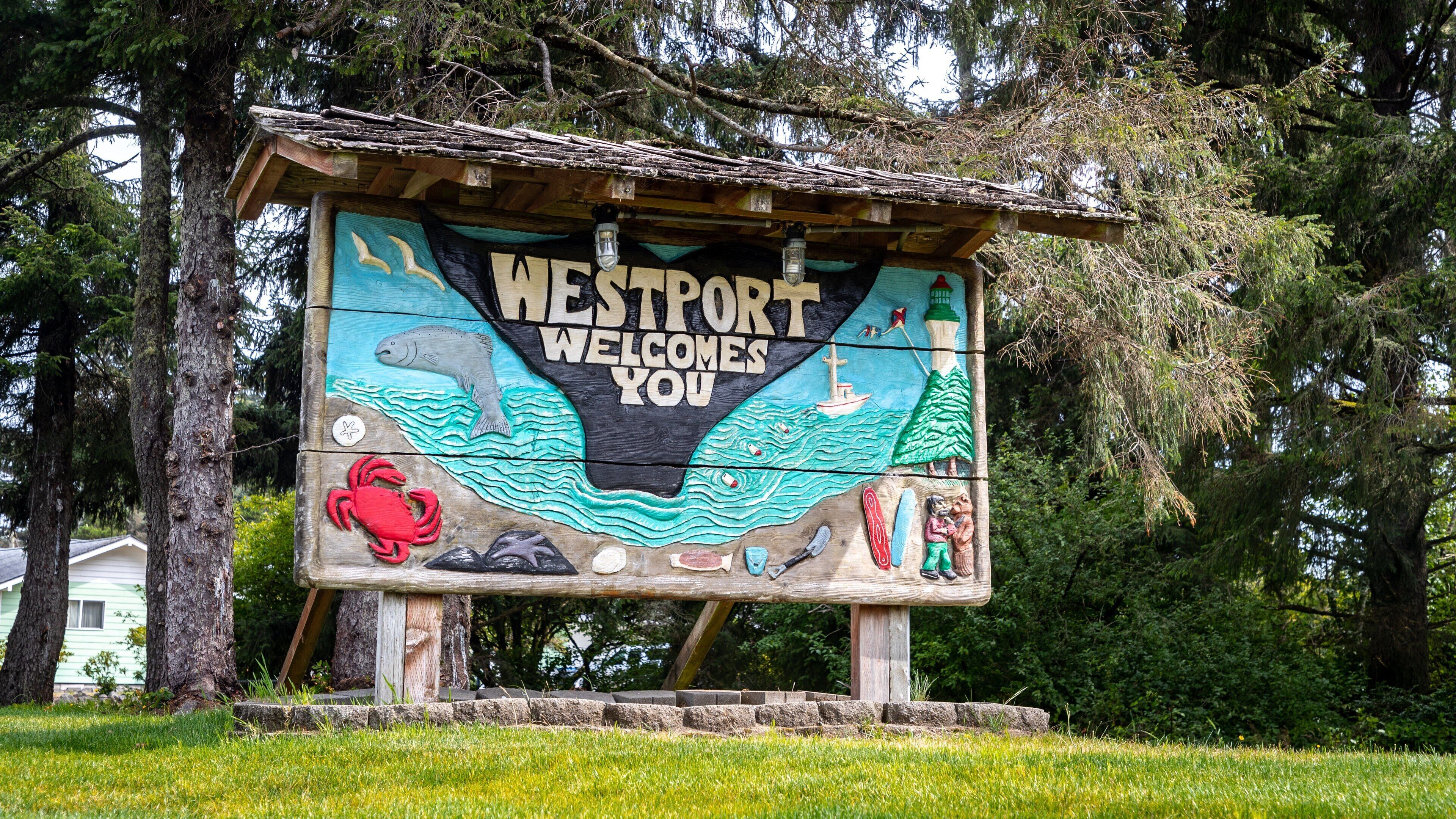 A wooden sign with 'Westport Welcomes You' and marine-themed artwork.