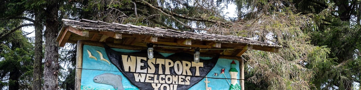 Ein Holzschild mit der Aufschrift 'Westport Welcomes You' und maritimen Illustrationen.
