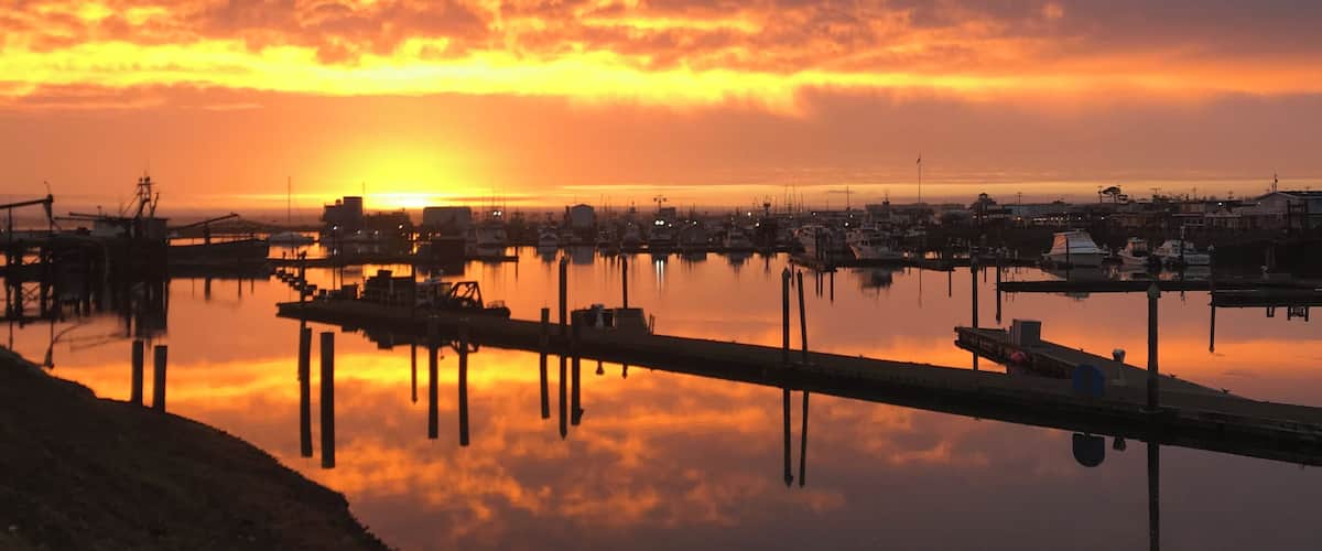 A sunset over a marina with boats and docks.