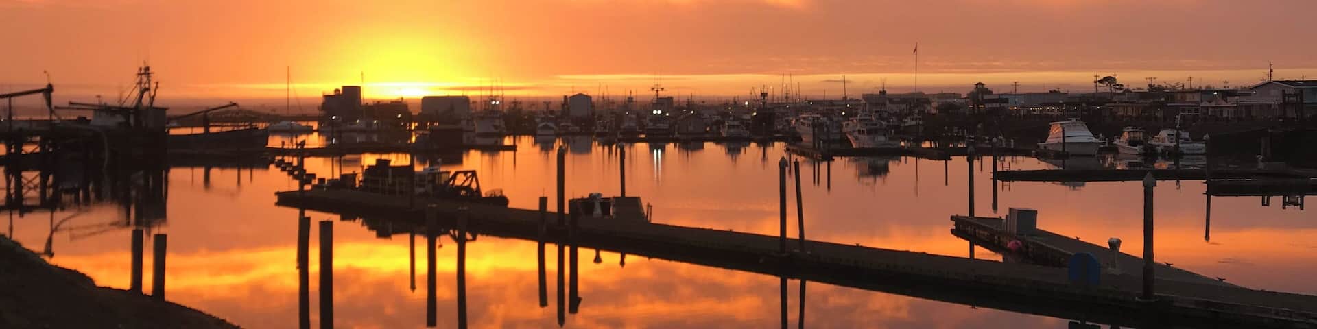 A sunset over a marina with boats and docks.