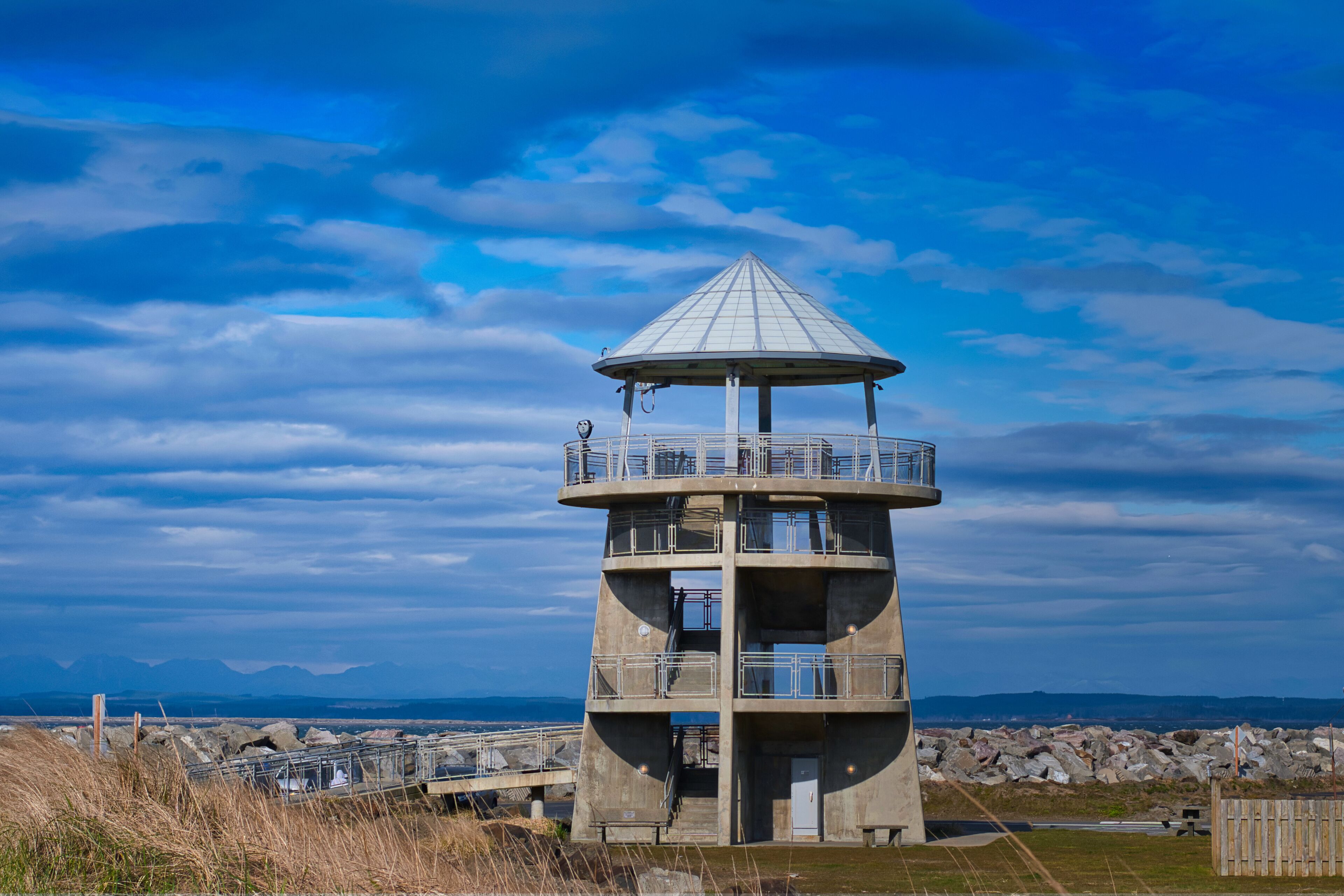 A concrete observation tower with a conical roof, surrounded by rocky terrain and a clear sky.