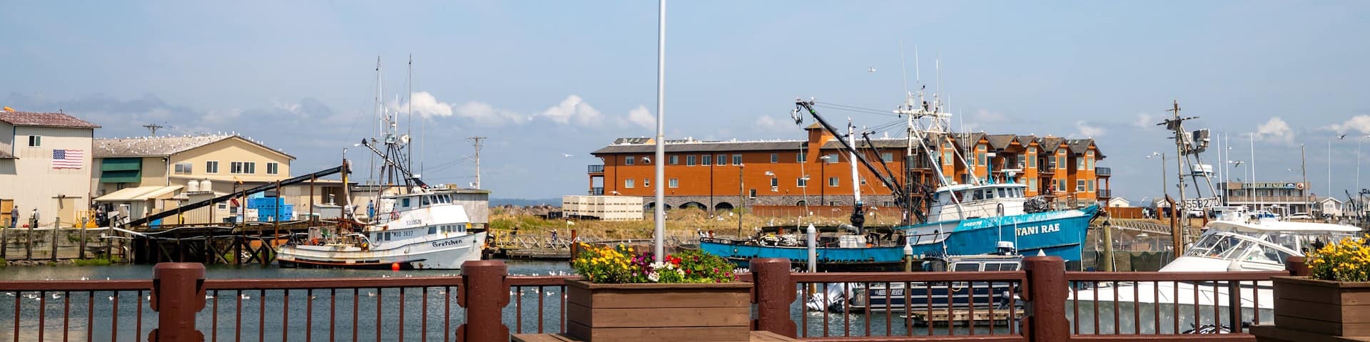 A marina with several boats, an American flag, and a building with a sign that reads "SANDY BEACH".