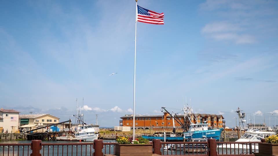 A marina with several boats, an American flag, and a building with a sign that reads "SANDY BEACH".