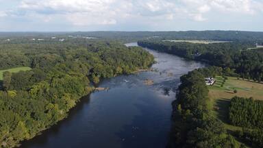 Aerial shot of Coosa river flowing between dense trees in Wetumpka, Alabama, Elmore County