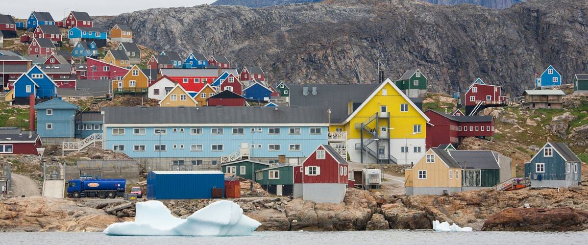 A coastal village with colorful houses, a truck, and an iceberg.