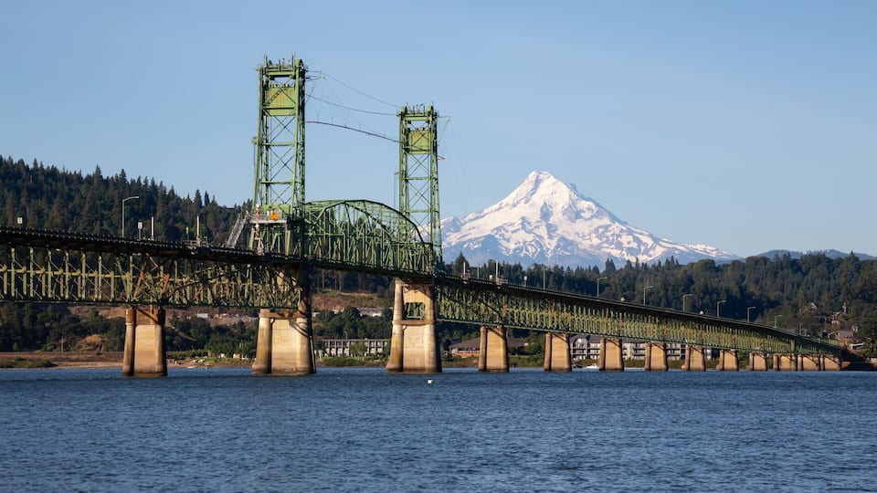 A bridge over water with a snow-capped mountain in the background.