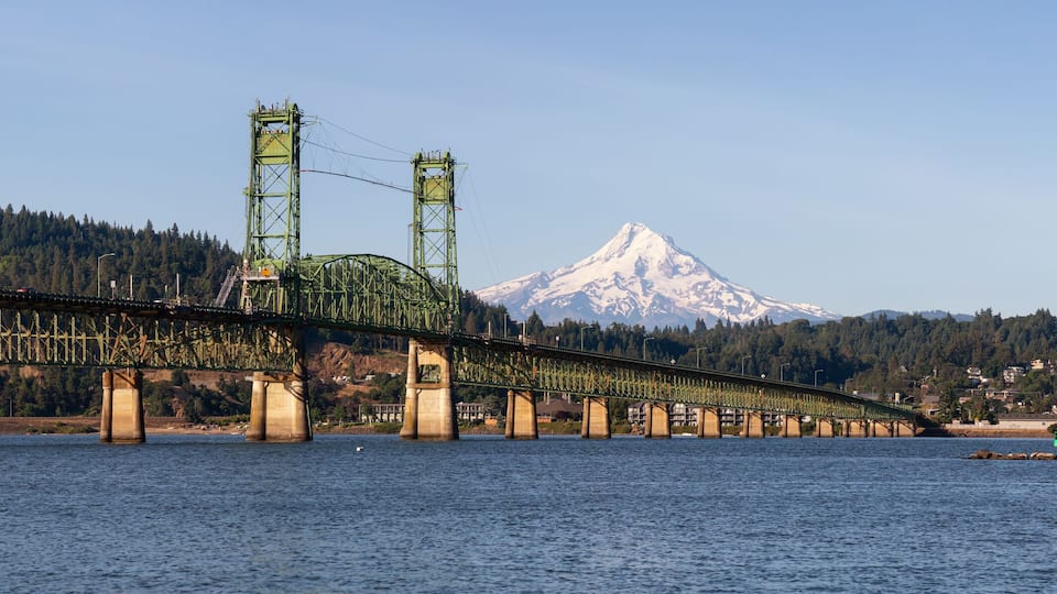 A bridge over a river with a mountain in the background.