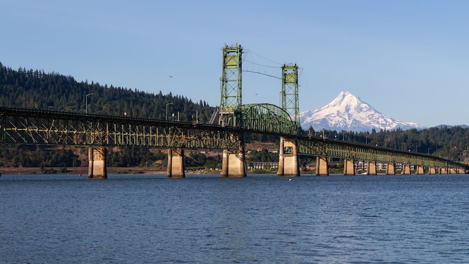 A bridge over a river with a mountain in the background.