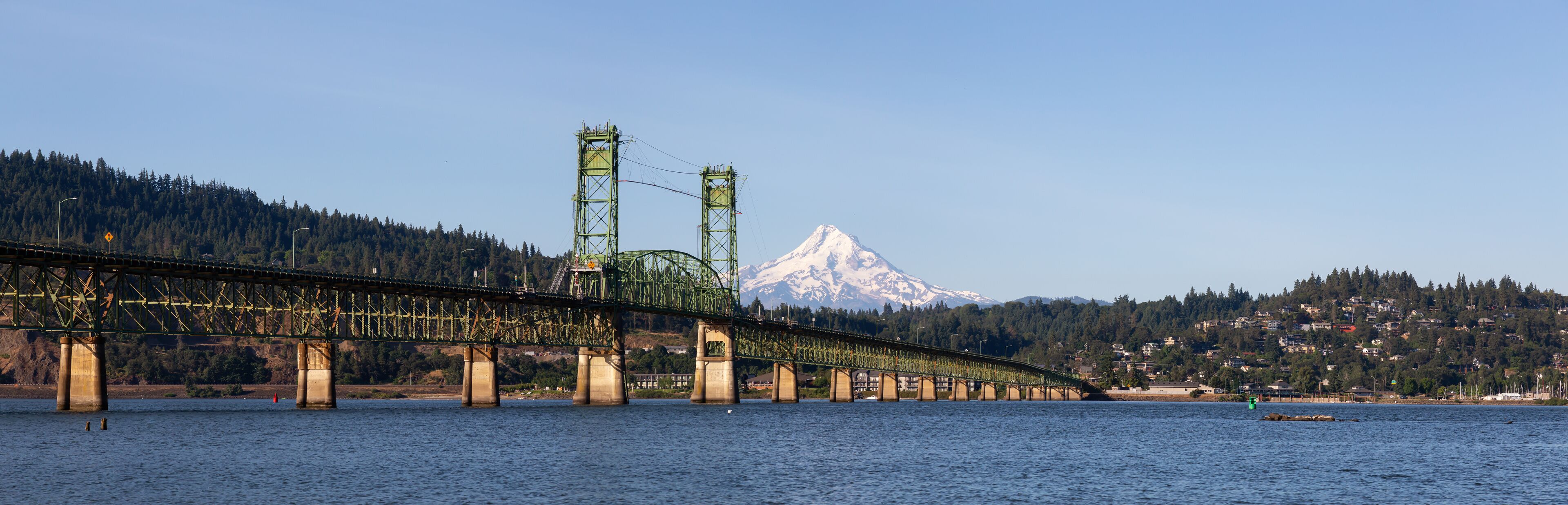 A long bridge spanning a river with a mountain in the background.