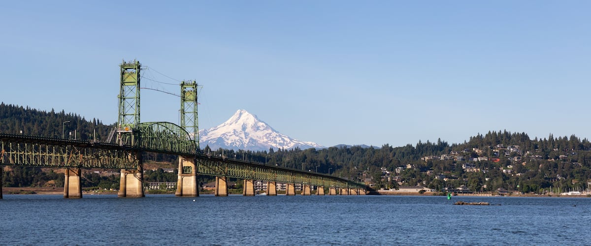 A long bridge spanning a river with a mountain in the background.