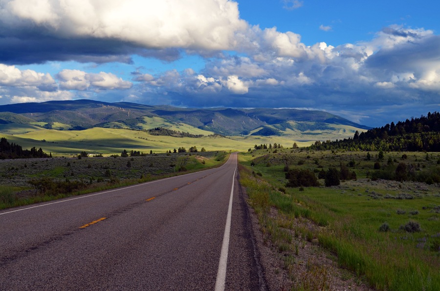 Un camino rural con cielo despejado y montañas a lo lejos.
