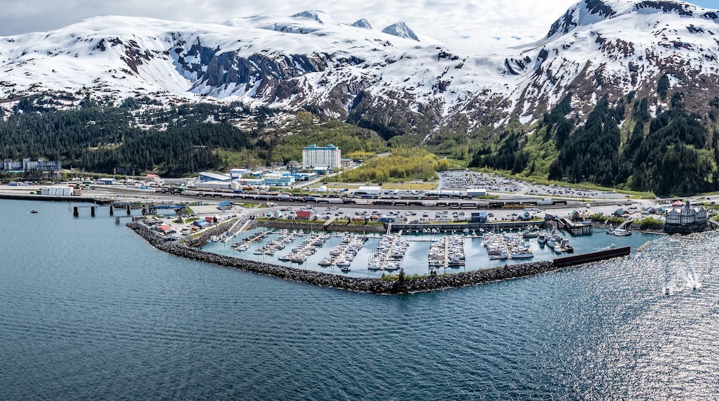 wide angle panoramic aerial landscape view of Whittier Cityscape with Harbor and Port located at head of Passage Canal in Alaska, USA, with snow covered mountain landscape in background