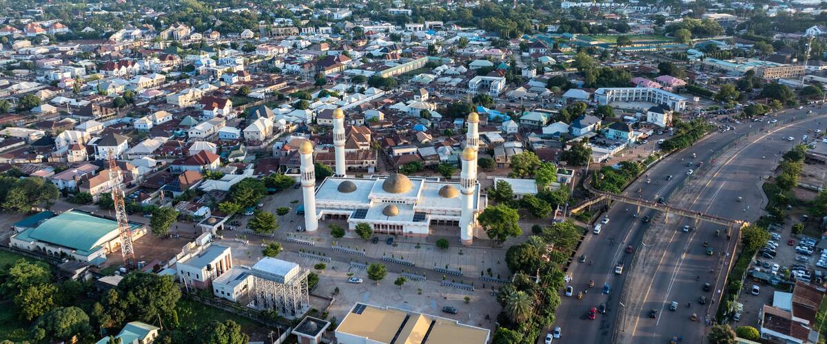 An aerial view of a city with a prominent mosque featuring golden domes and minarets, surrounded by residential and commercial buildings.
