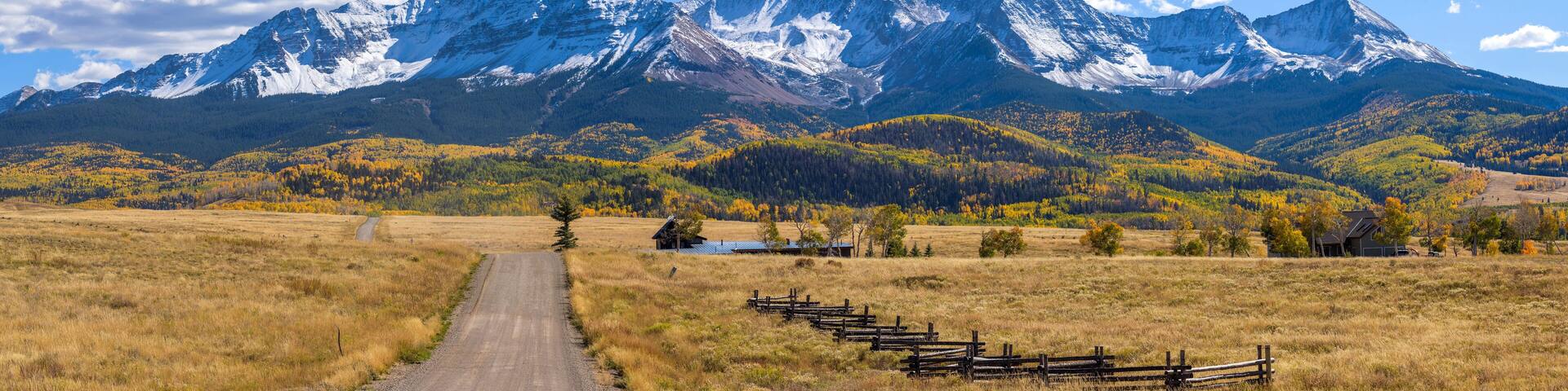Autumn Mountain Country-Road - A panoramic Autumn view of a country road extending towards towering snow-capped Wilson Peak. Telluride, Colorado, USA.