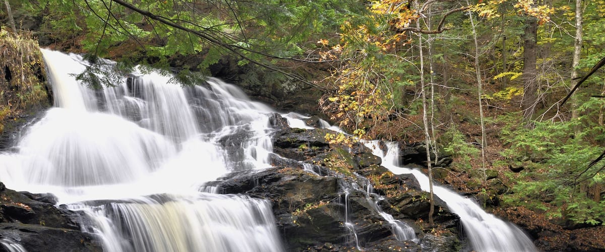 A multi-tiered waterfall surrounded by autumn foliage.
