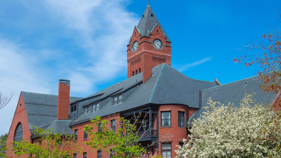 A historic building with a clock tower, red brick walls, and a green roof.