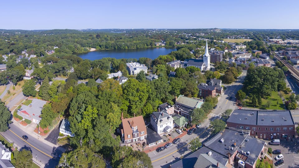 An aerial view of a town with a lake, church steeples, and a bridge.
