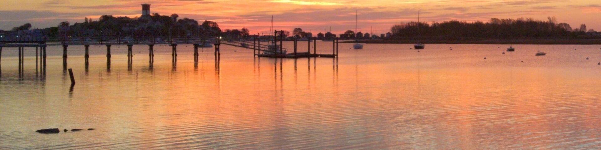 Un atardecer sobre un lago tranquilo con un muelle que se adentra en el agua.
