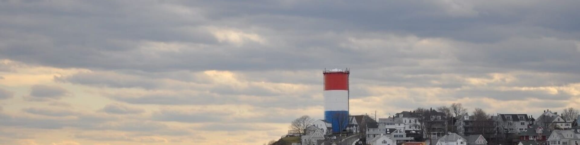 As seen from Deer Island, this is the town of Winthrop, just north of Boston, MA.  It's a cute, condensed town with houses stacked right on top of each other on the hills.  The long beach (the end of which you can see in the photo) is a great place to walk in winter, and of course is packed in the summer.  Get there early to find a parking space!