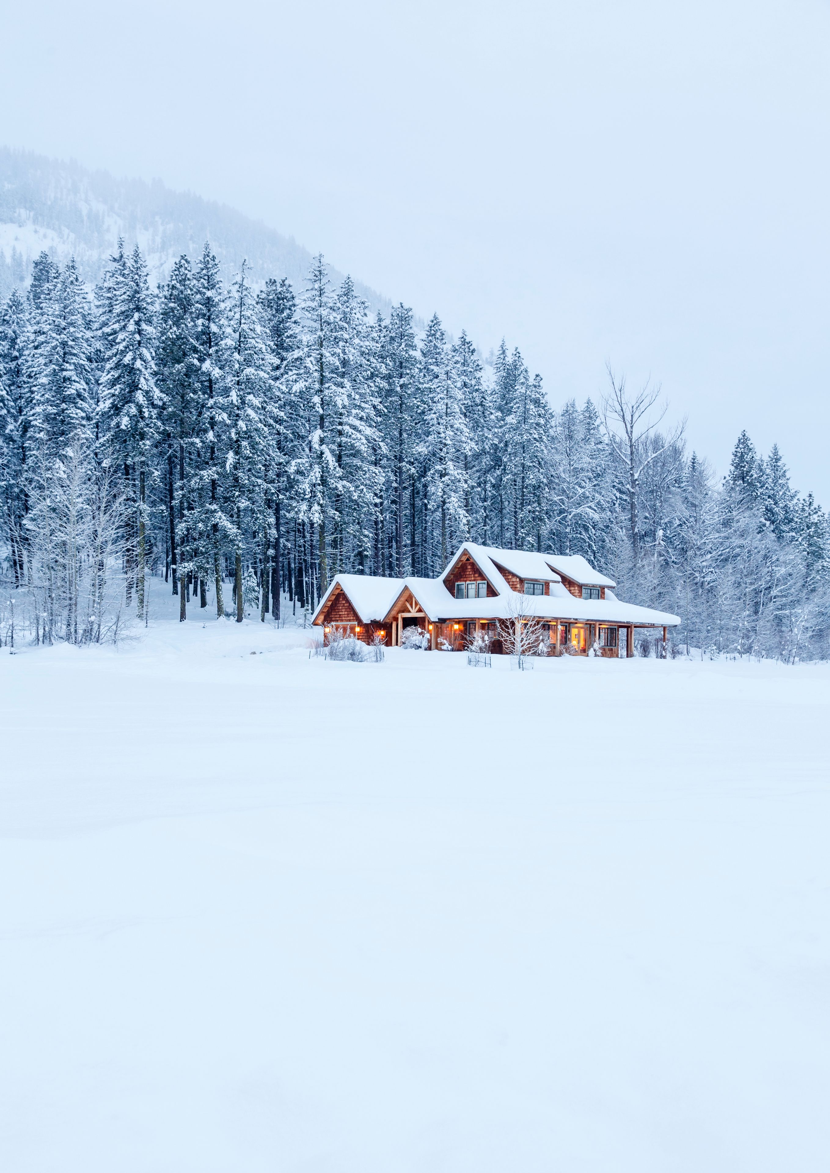 A snow-covered lodge with multiple wooden cabins in a forest.