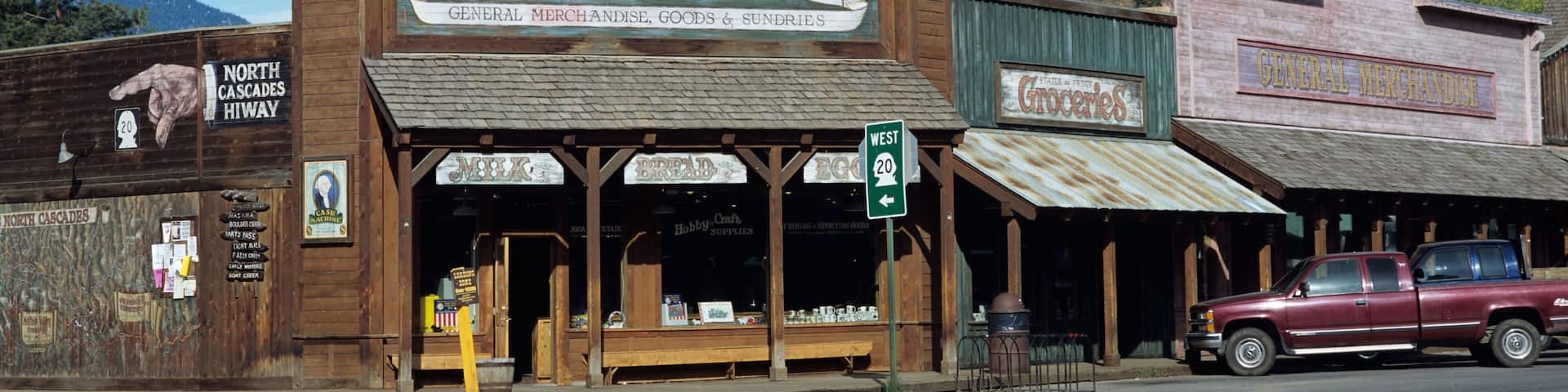 A vintage building with a sign reading "Welcome to Winthrop Emporium" and a vintage car parked outside.