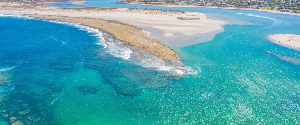 A coastal landscape with clear turquoise waters, sandy beaches, and a distant town.