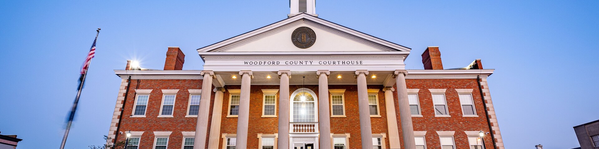 Woodford county clubhouse in Versailles, Kentucky during sunrise. Early morning traffic crossing the street in front of the building.