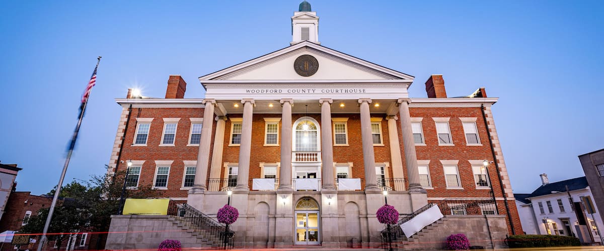 A large brick courthouse with a central dome and columns, surrounded by a well-maintained lawn and a flagpole.
