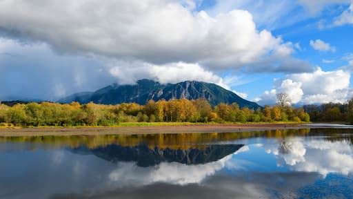 Mount Si reflects in Borst Lake in late fall under partly cloudy sky hanging on the top of the peak in Snoqualmie Washington