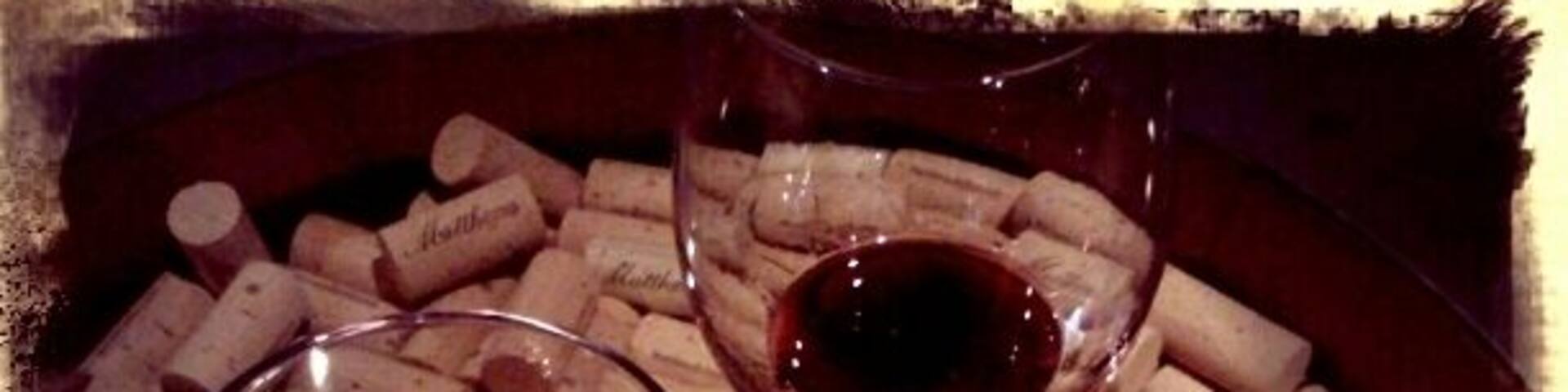 Two wine glasses filled with red wine, surrounded by wine corks, and a wooden coaster with "Woodinville Wine Country" written on it.