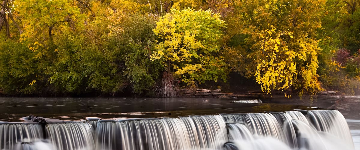 A waterfall with multiple tiers, surrounded by autumn foliage.