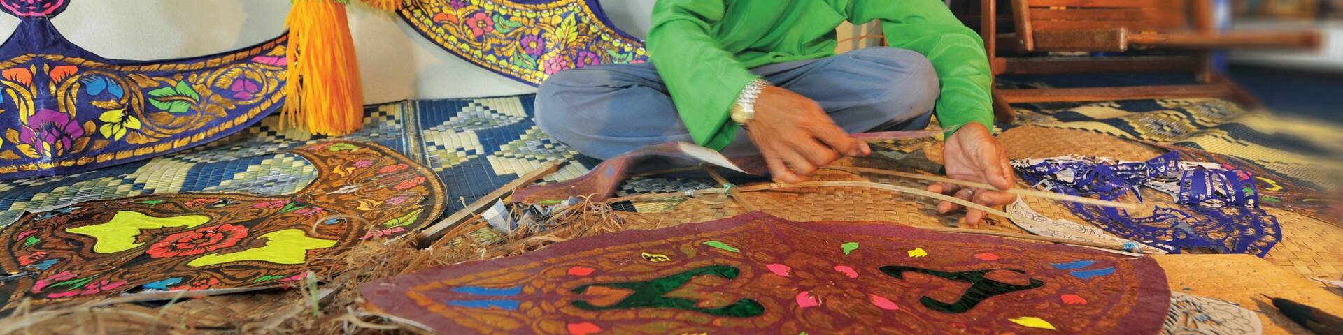 A person working on a colorful textile with intricate patterns.