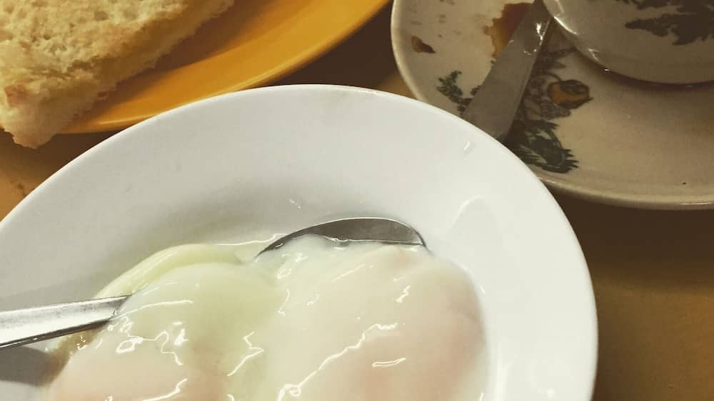 A plate with a poached egg and toast, a cup with floral design, and a knife on a saucer.