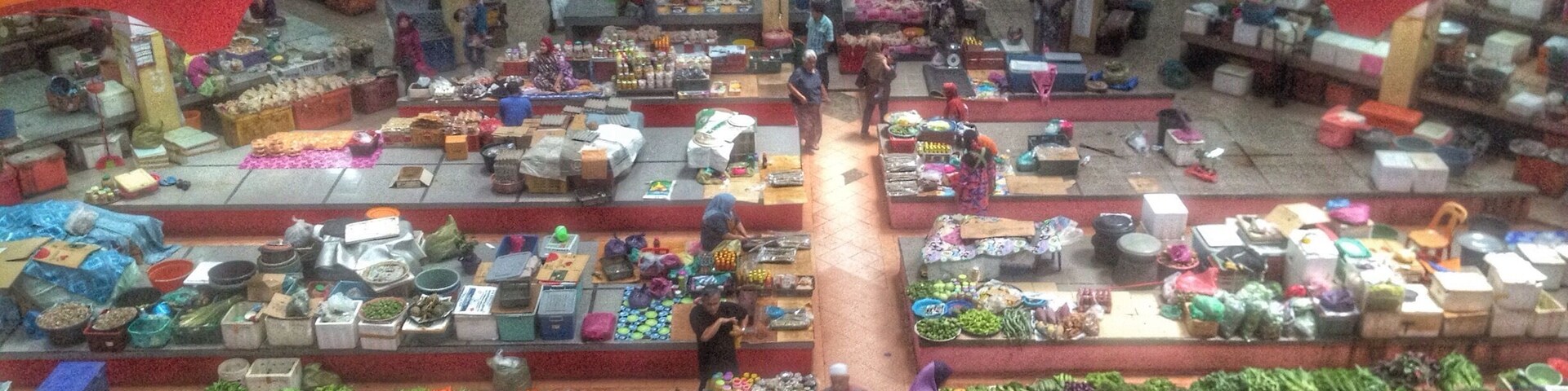 An indoor market with various stalls selling fruits, vegetables, and other goods.