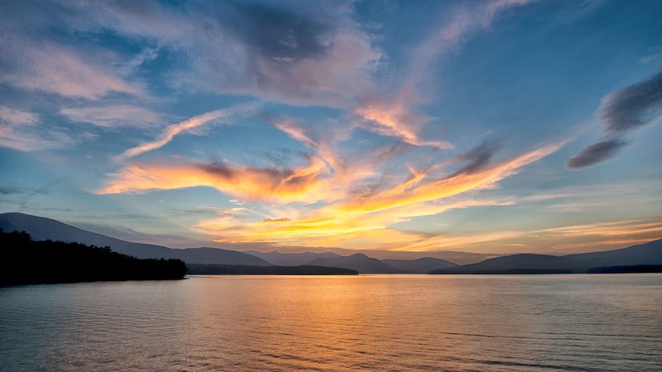 Dramatic Sunset with Blue Sky at the Ashokan Reservoir in Ulster County in New York. Golden light reflects on the Mountains and calm reservoir surface.