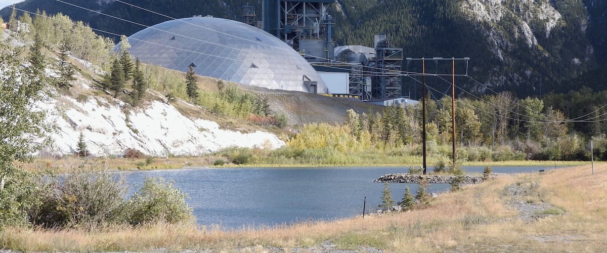 A hydroelectric dam with a large water reservoir and a mountain backdrop.