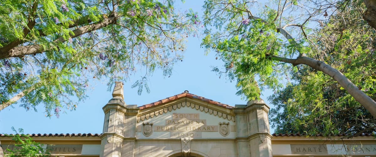 The South Pasadena Public Library entrance with a community room sign, surrounded by trees.