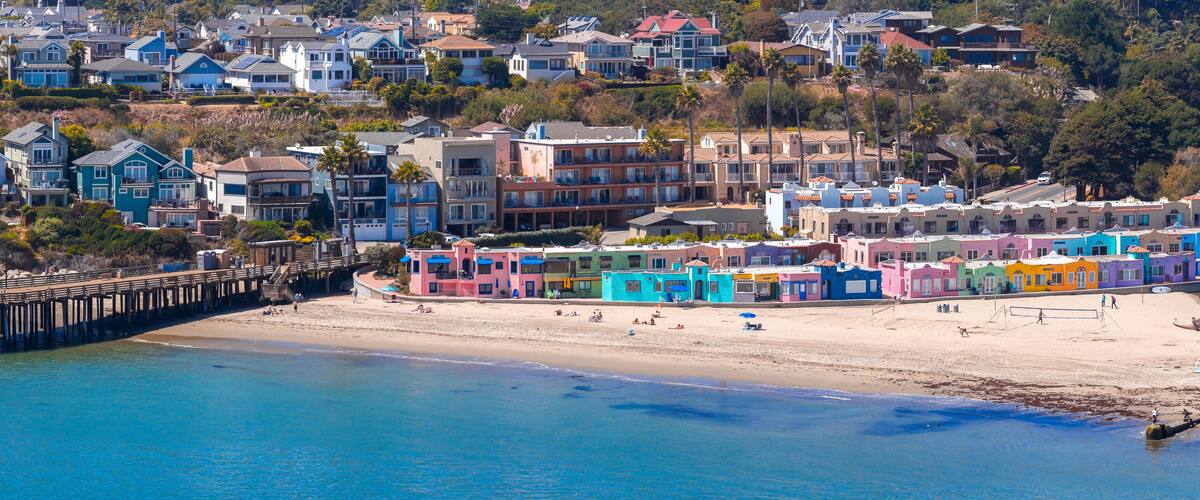 A coastal town with colorful houses, a pier, and a beach.