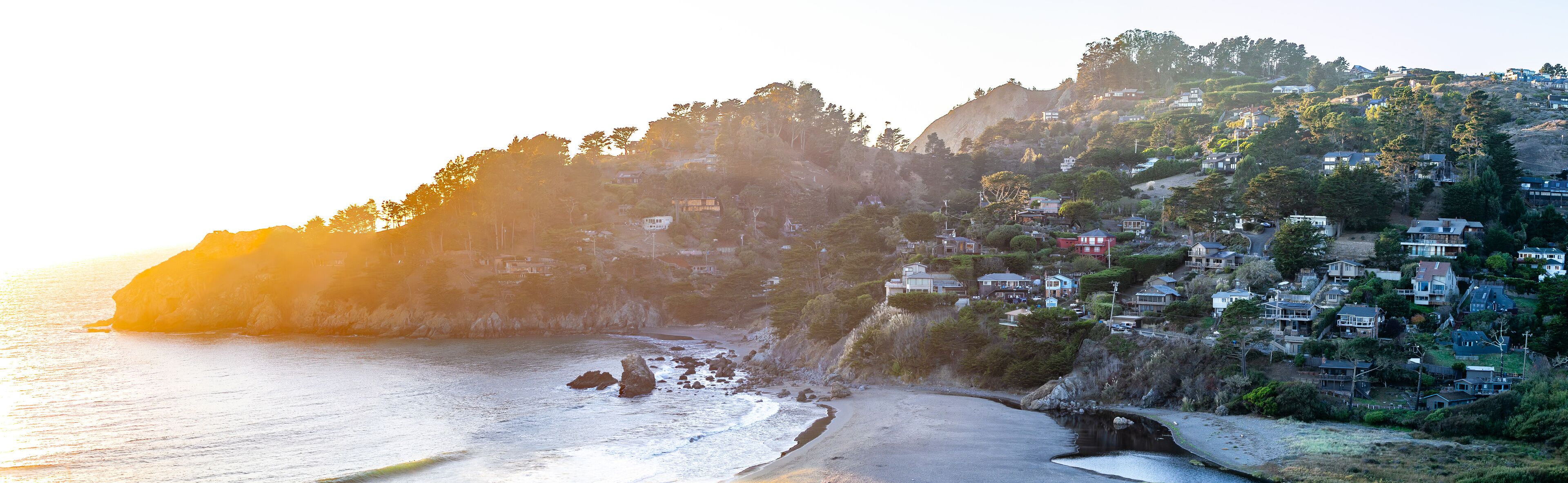 Scenic view of Muir Beach coastline in California with waves crashing against the rocky shore and a clear blue sky in the background