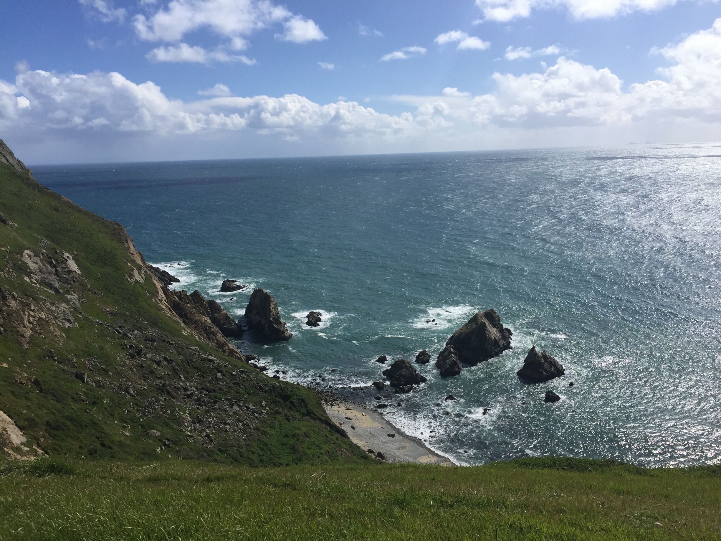 A coastal landscape with rocky outcrops and a grassy cliffside.