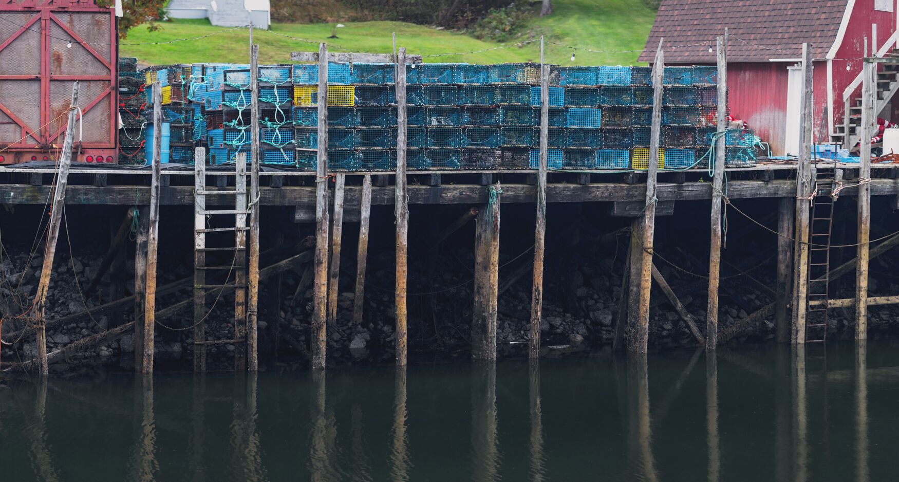 A dock with wooden posts and a red building in the background.