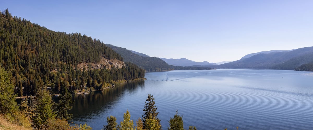 A calm lake surrounded by dense forests and mountains.