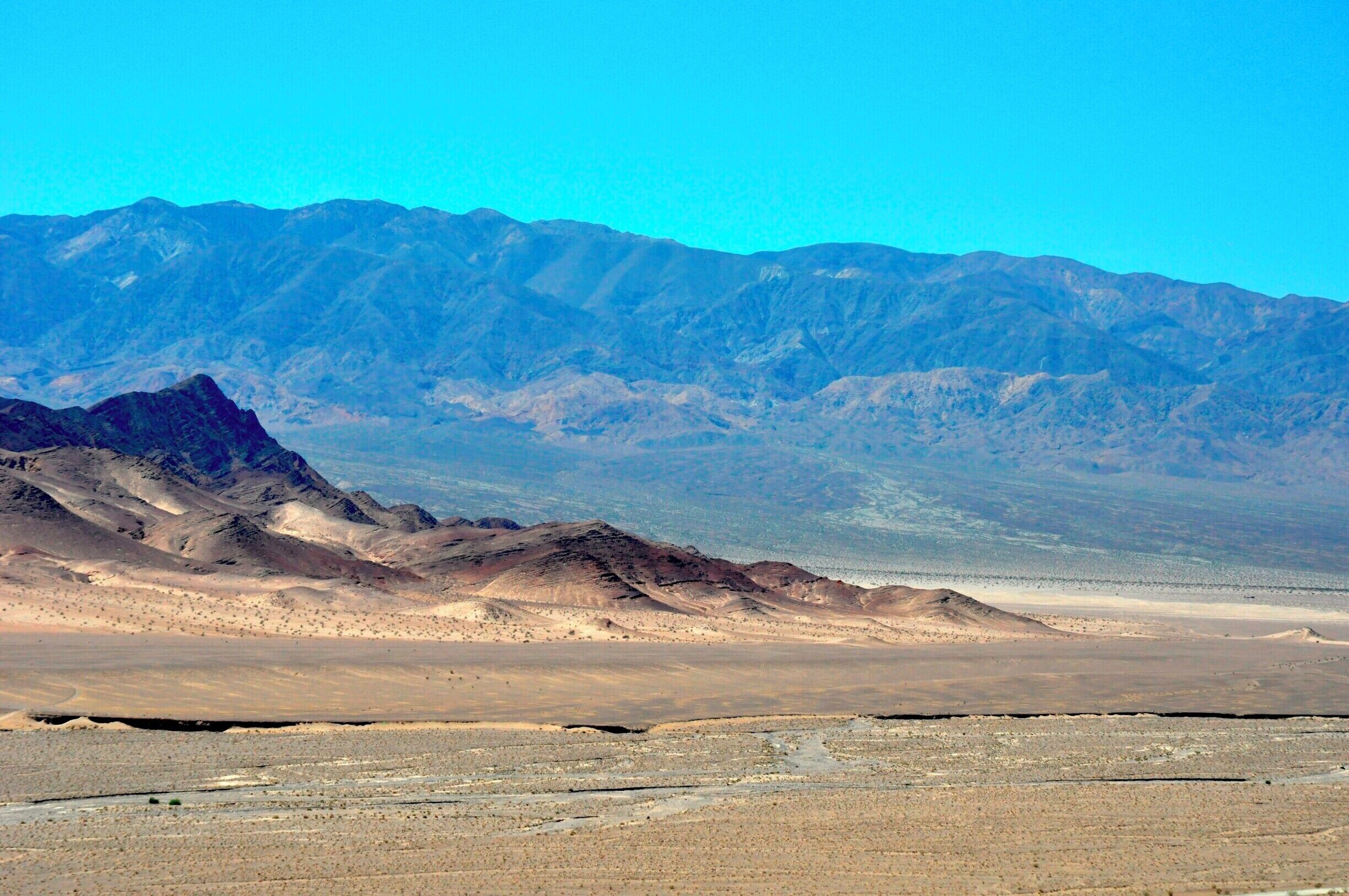 The basins of Death Valley sink below sea level and are surrounded by sharp mountain ranges, leading to searing temperatures during the summer. The resulting basins are so flat and empty that the enormous mountains in the distance appear #blue in the crisp desert air. #BestOf5